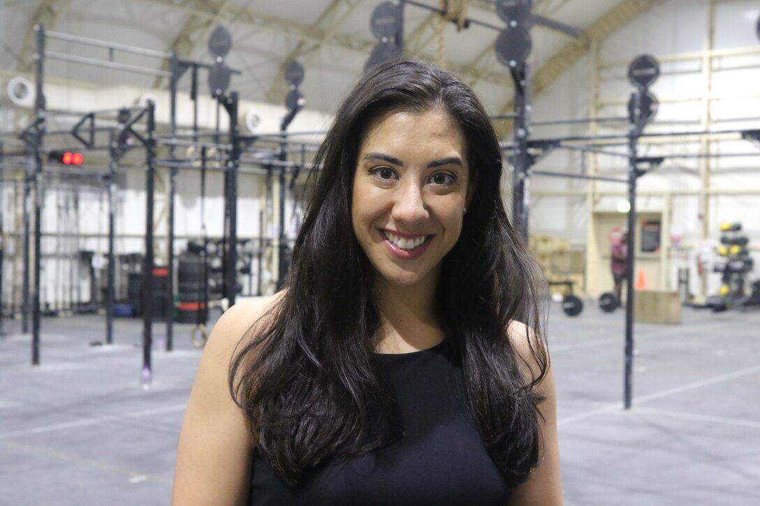 A woman poses for a photo in front of fitness equipment.