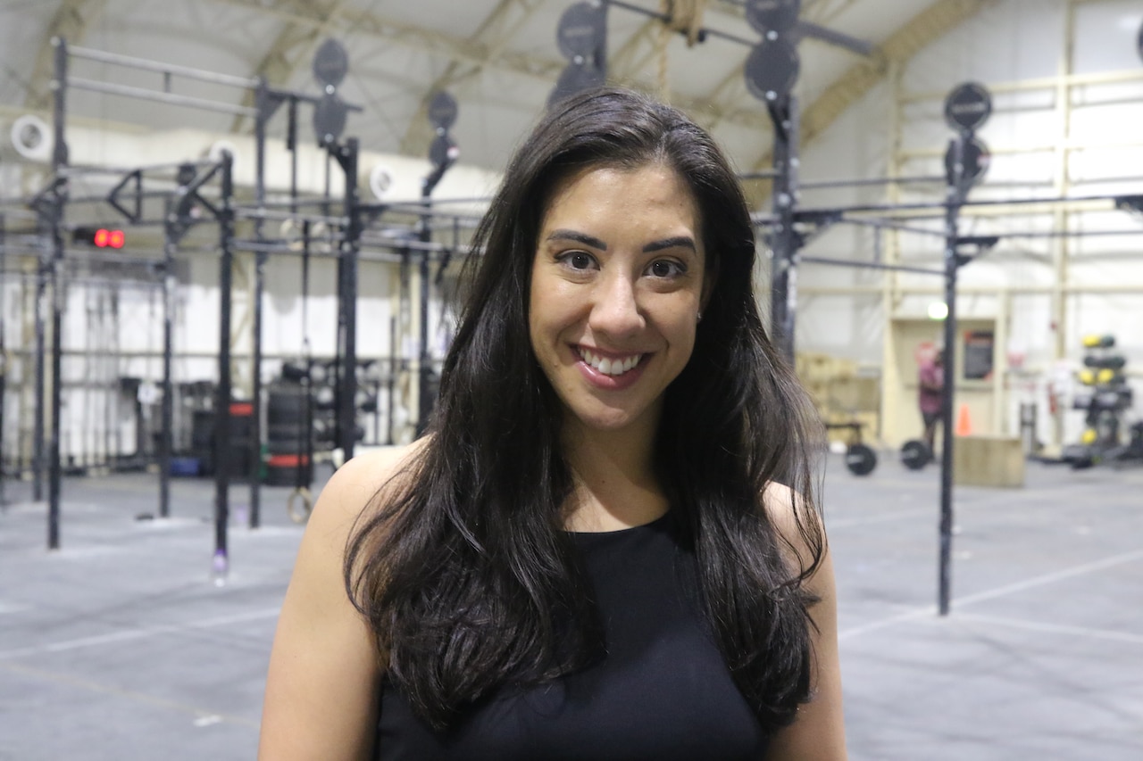 A woman poses for a photo in front of fitness equipment.