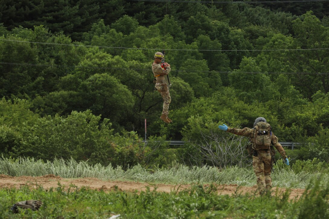 Sgt. Jake Mellott, verifies the casualty is safely hoisted to the HH-60M MEDEVAC Helicopter while hovering overhead, September 1, 2022, Korea Combat Training Center, Republic of Korea. The hoist is used for evacuations where the aircraft cannot land to pick up a casualty in a timely manner. (U.S. Army photo by Sgt. Oscar Toscano)