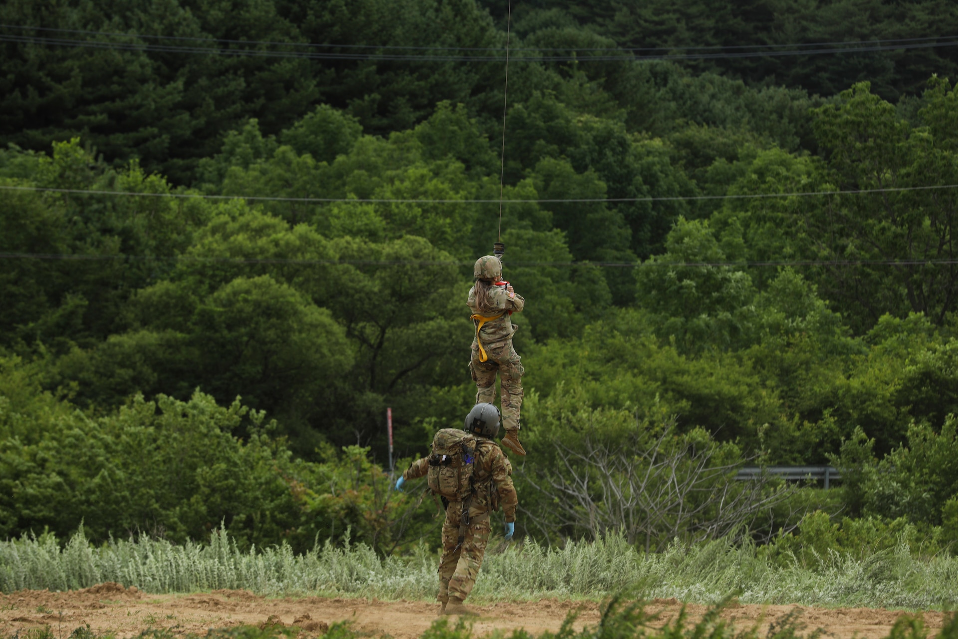 Sgt. Jake Mellott, verifies the casualty is safely hoisted to the HH-60M MEDEVAC Helicopter while hovering overhead, September 1, 2022, Korea Combat Training Center, Republic of Korea. The hoist is used for evacuations where the aircraft cannot land to pick up a casualty in a timely manner. (U.S. Army photo by Sgt. Oscar Toscano)