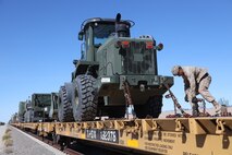 U.S Marine Corps Cpl. Tristan Romero, landing support technician, 2nd Landing Support Battalion, 2nd Marine Logistics Group, secures a vehicle onto a train car during railroad operations amid Weapons and Tactics Instructor (WTI) Course 1-23 near Glamis, California, Nov. 4, 2022. The Marine Corps Air Station Yuma, Arizona, Distribution Management Office assisted 1st Landing Support Battalion, 1st MLG and 2nd Transportation Battalion, 2nd MLG, as they loaded equipment being extracted from WTI onto train cars, Oct. 31 to Nov. 7, 2022. (U.S. Marine Corps photo by Lance Cpl. Jon C. Stone)