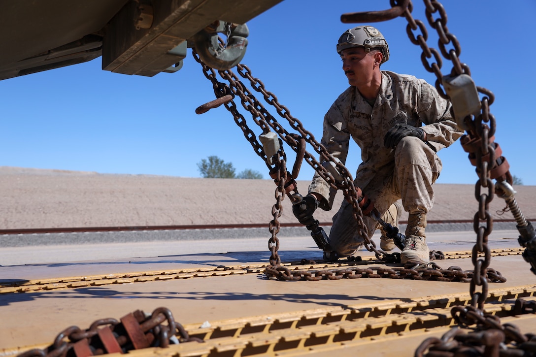 U.S Marine Corps Cpl. Tristan Romero, Landing Support Technician, 2nd Landing Support Battalion, 2nd Marine Logistics Group, secures a vehicle onto a train car during railroad operations amid Weapons and Tactics Instructor (WTI) Course 1-23 near Glamis, California, Nov. 4, 2022.