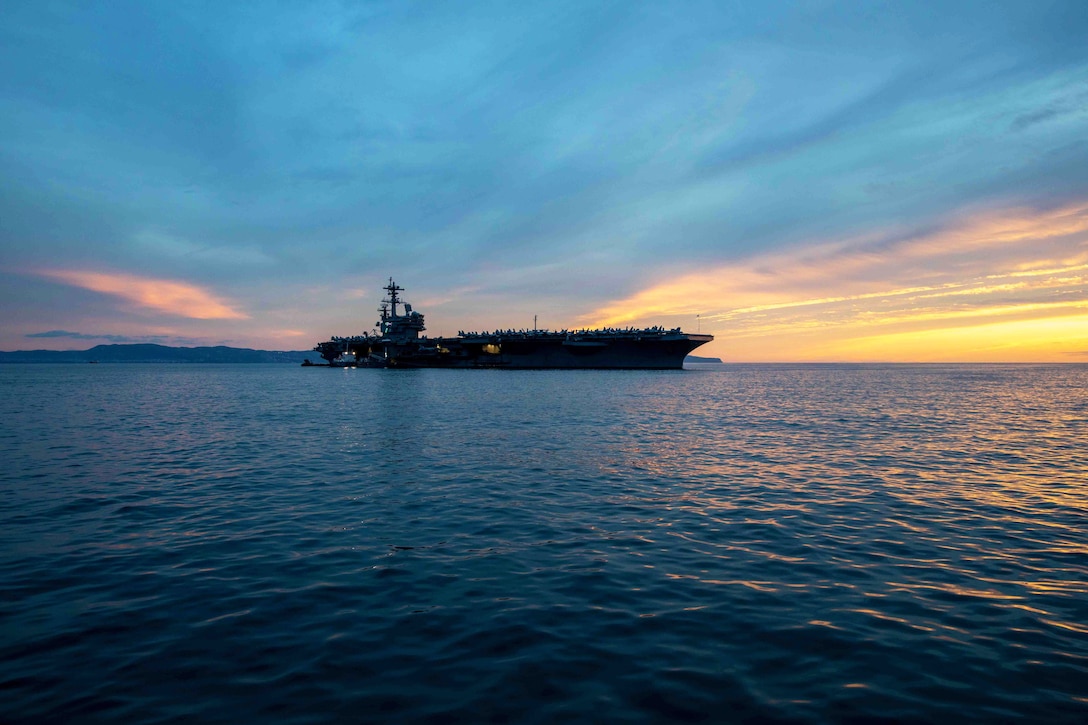 A ship is seen in the distance under a bluish-cloudy sky with golden hues on either side.