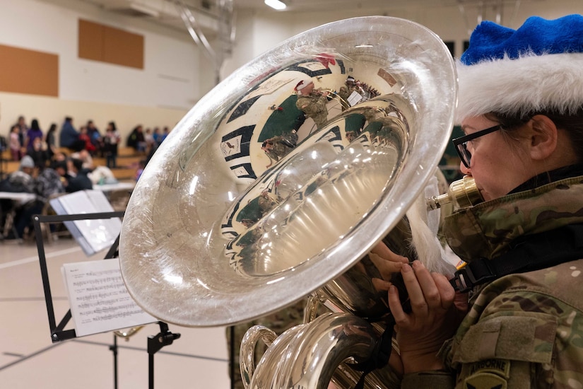 U.S. Army Staff Sgt. Bethany Hyson, a musician with the 11th Airborne Division Band, plays the tuba during Operation Santa Claus at the Trapper School in Nuiqsut, Alaska, Nov. 29, 2022. Santa, Mrs. Claus and more than three dozen elves from the Alaska Air and Army National Guard partnered with the Salvation Army to deliver 1,420 pounds of gifts, hygiene supplies, and books to 191 children. Celebrating 67 years of Operation Santa Claus, a 176th Wing, Alaska Air National Guard HC-130J Combat King II aircraft served as Santa's sleigh, delivering tidings of good cheer to the North Slope Borough community
