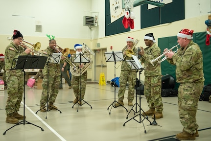 Musicians with the 11th Airborne Division Band play seasonal tunes and Christmas carols during the Operation Santa Claus celebration at the Trapper School in Nuiqsut, Alaska, Nov. 29, 2022. Santa, Mrs. Claus and more than three dozen elves from the Alaska Air and Army National Guard partnered with the Salvation Army to deliver 1,420 pounds of gifts, hygiene supplies, and books to 191 children. Celebrating 67 years of Operation Santa Claus, a 176th Wing, Alaska Air National Guard HC-130J Combat King II aircraft served as Santa's sleigh, delivering tidings of good cheer to the North Slope Borough community.