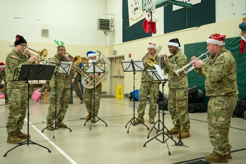 Musicians with the 11th Airborne Division Band play seasonal tunes and Christmas carols during the Operation Santa Claus celebration at the Trapper School in Nuiqsut, Alaska, Nov. 29, 2022. Santa, Mrs. Claus and more than three dozen elves from the Alaska Air and Army National Guard partnered with the Salvation Army to deliver 1,420 pounds of gifts, hygiene supplies, and books to 191 children. Celebrating 67 years of Operation Santa Claus, a 176th Wing, Alaska Air National Guard HC-130J Combat King II aircraft served as Santa's sleigh, delivering tidings of good cheer to the North Slope Borough community.