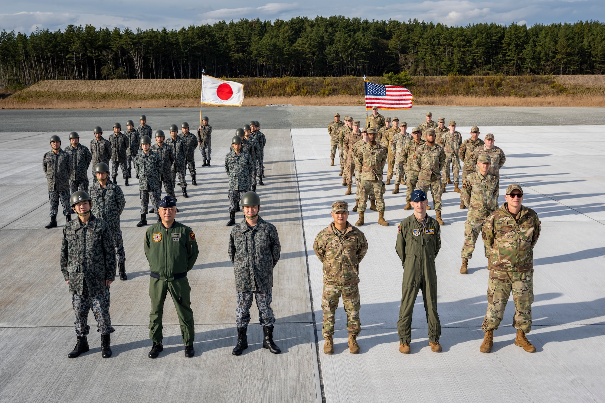 U.S. Air Force and Japan Air Self-Defense Force members, assigned to the 35th Civil Engineer Squadron and the Northern Air Civil Engineering Group, attend a ceremony to commemorate the completion of a bilateral Rapid Airfield Damage Recovery (RADR) pad at Draughon Range near Misawa Air Base, Japan, Nov. 29, 2022.