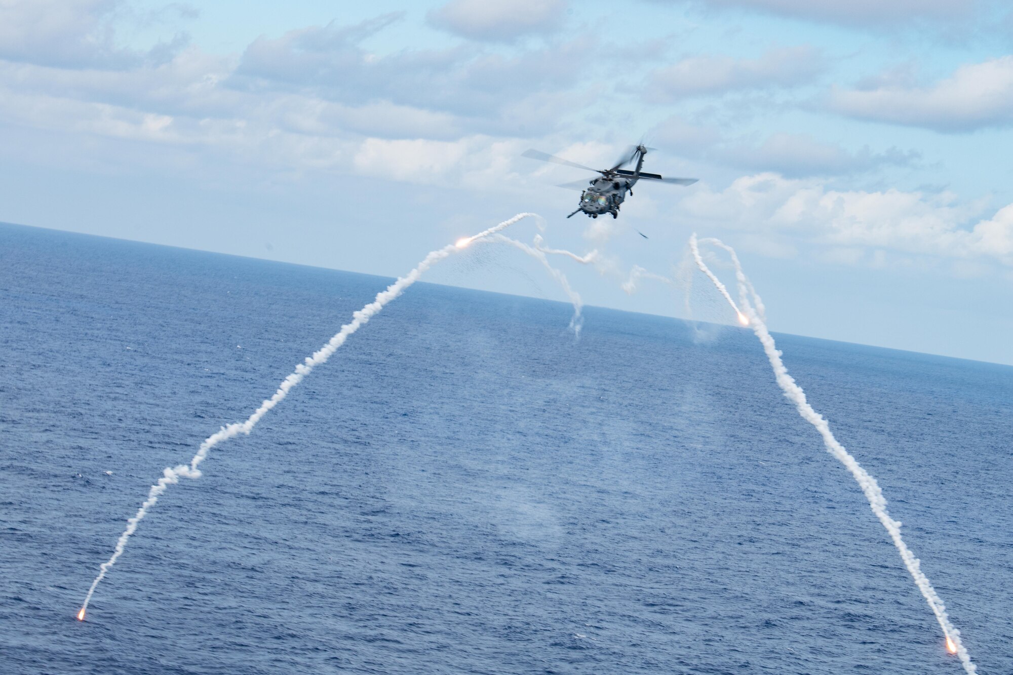 A helicopter shoots flares over the ocean