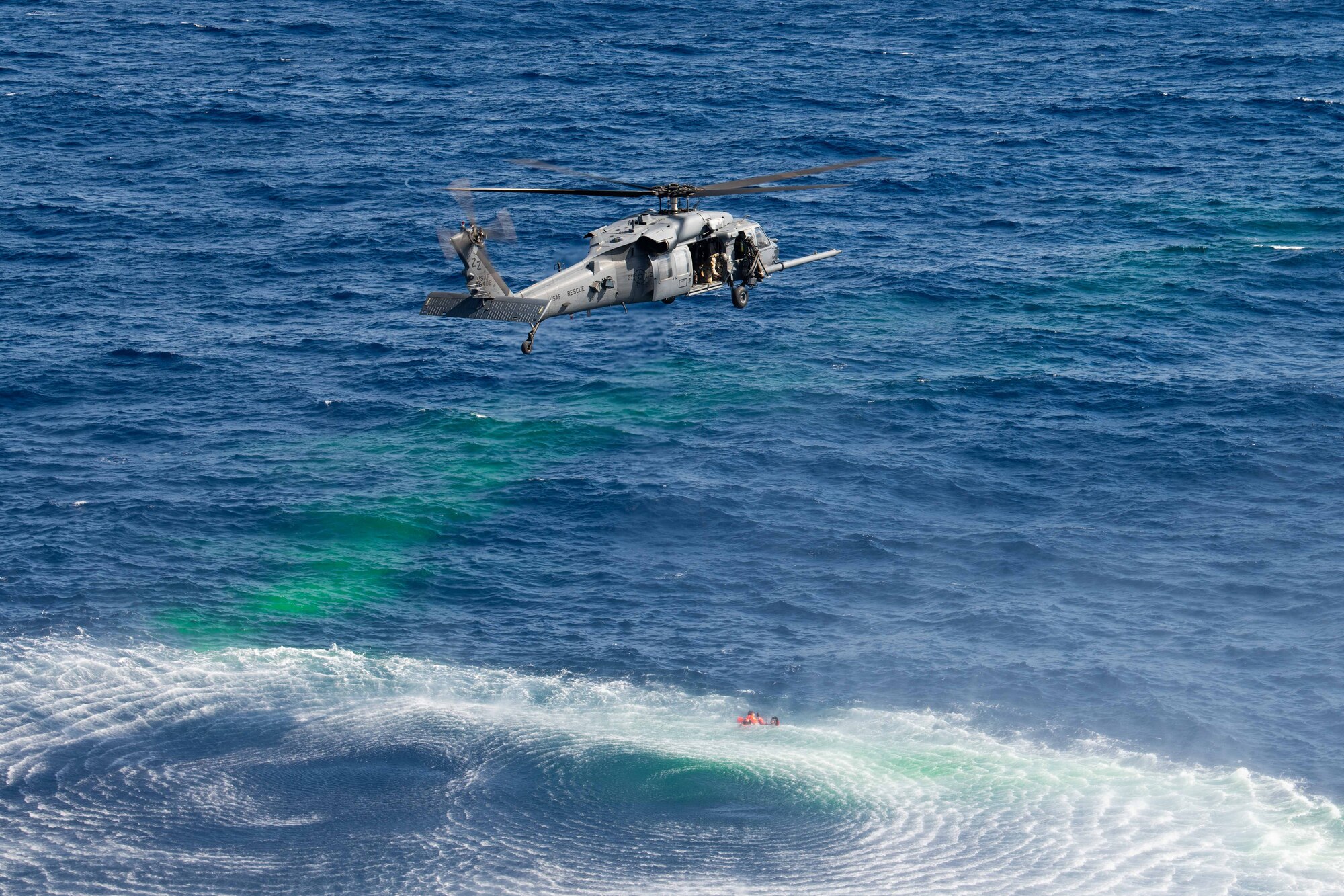 A helicopter flies over a bunch of divers and dye waiting in the ocean for rescue