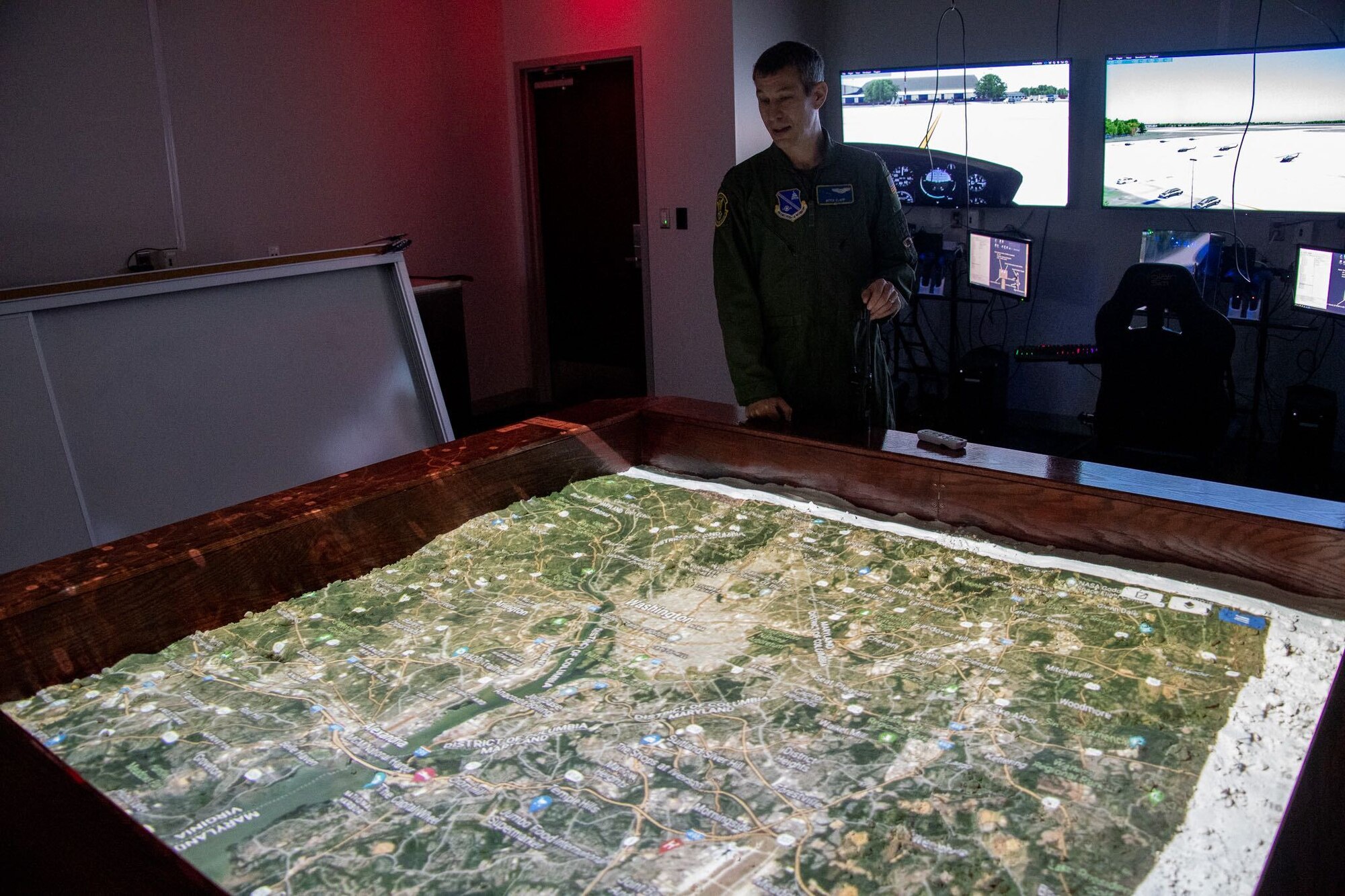 Maj. Mitchell Clapp, 316th Operations Support Squadron assistant director of operations, observes a virtual-reality helicopter training mission digitally projected over “The Sand Table,” a raised fixture filled with hand-formed sand to model the National Capital Region terrain, at Joint Base Andrews, Maryland, Oct. 25, 2022.