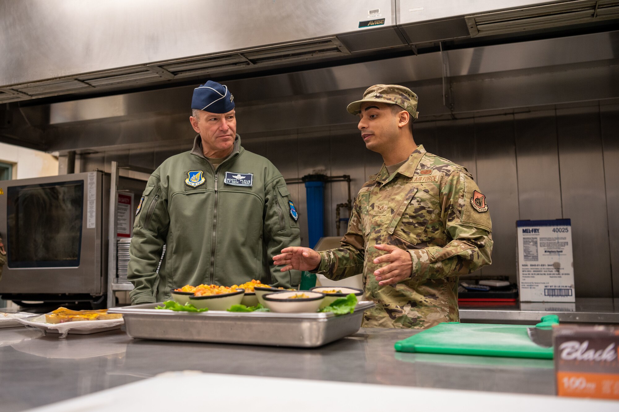 U.S. Air Force Senior Airman Reshaun Ali, 51st Force Support Squadron food service journeyman, showcases vegetarian and vegan meal options to Lt. Gen. Scott Pleus, 7th Air Force commander, at the Gingko Tree dining facility on Osan Air Base, Republic of Korea, Nov. 30, 2022.