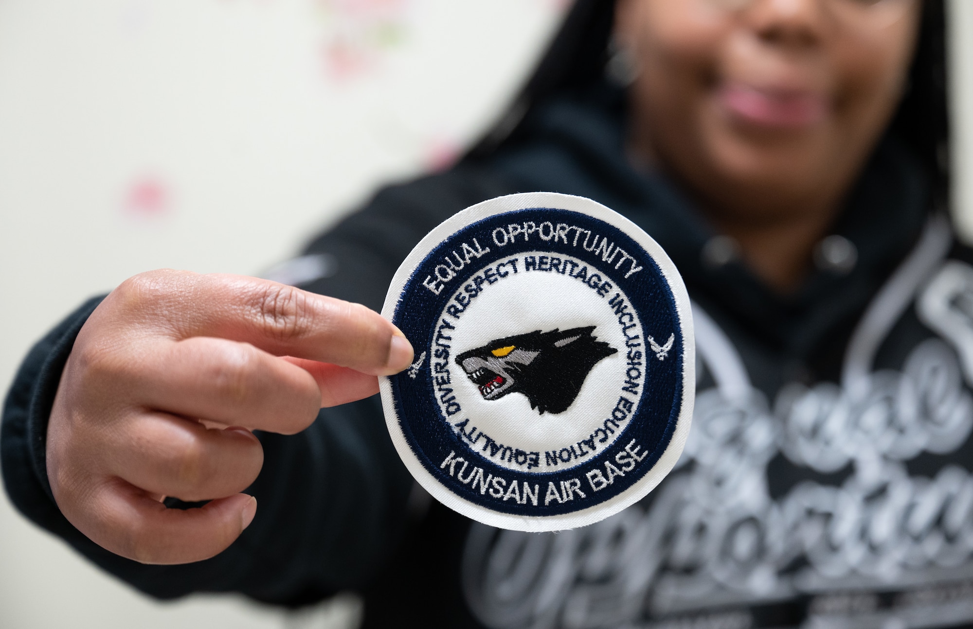 U.S. Air Force Staff Sgt. Dasha Harris, 8th Fighter Wing Equal Opportunity NCO in charge, shows an EO morale patch at Kunsan Air Base, Republic of Korea, Dec. 2, 2022. Harris works as both the EO NCOIC and the Wing Military Resiliency Trainer and holds trainings that help foster inclusivity within the workspace. (U.S. Air Force photo by Staff Sgt. Sadie Colbert)