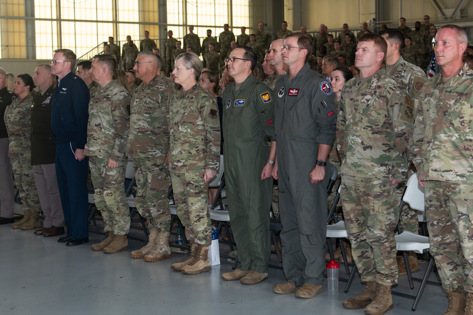 Leadership from the Virginia National Guard stand at a attention in the audience.