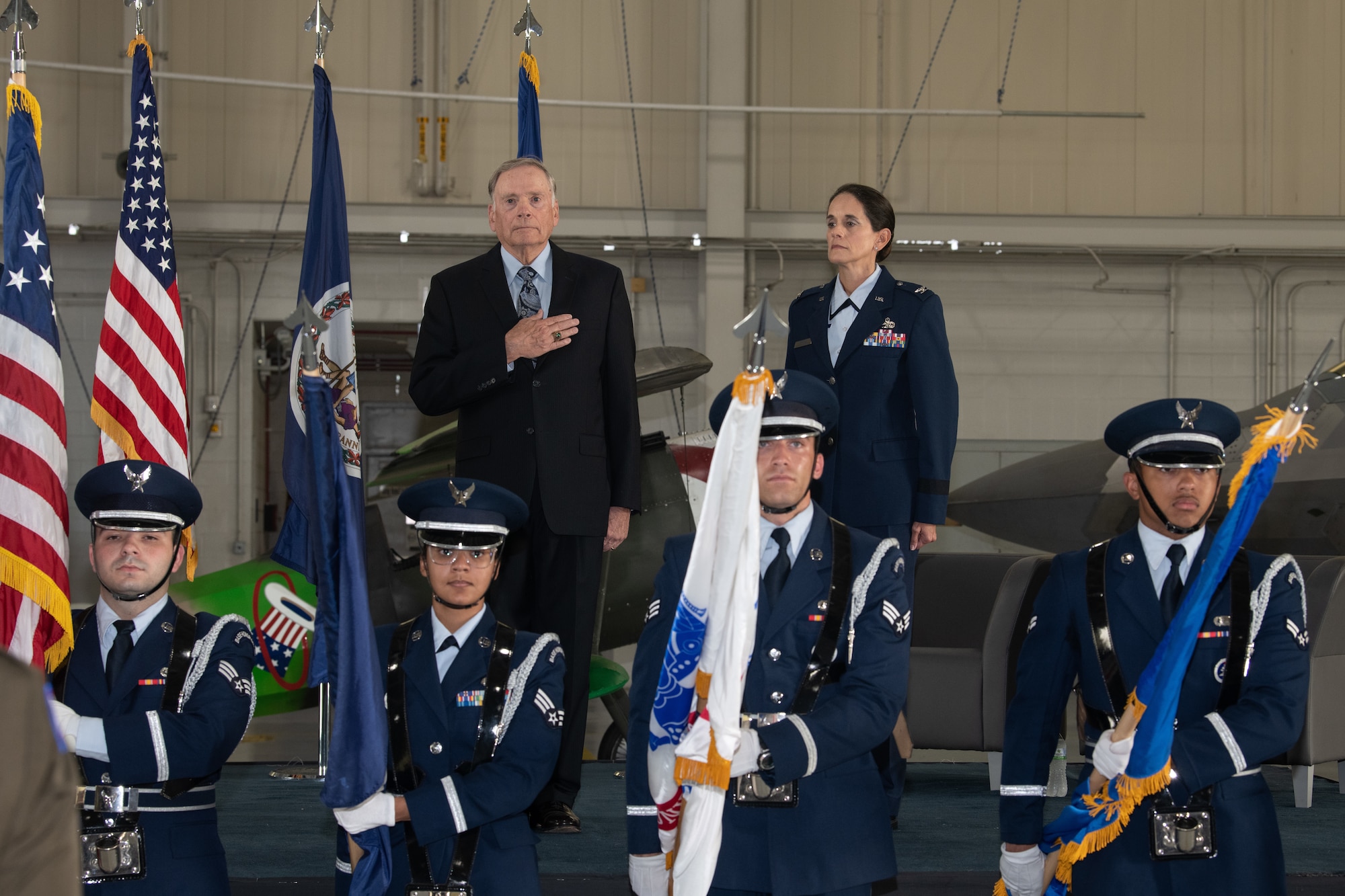 Gen. John P. Jumper and Col. Catherine M. Jumper stand on stage while the Honor Guard presents the colors for the National Anthem.