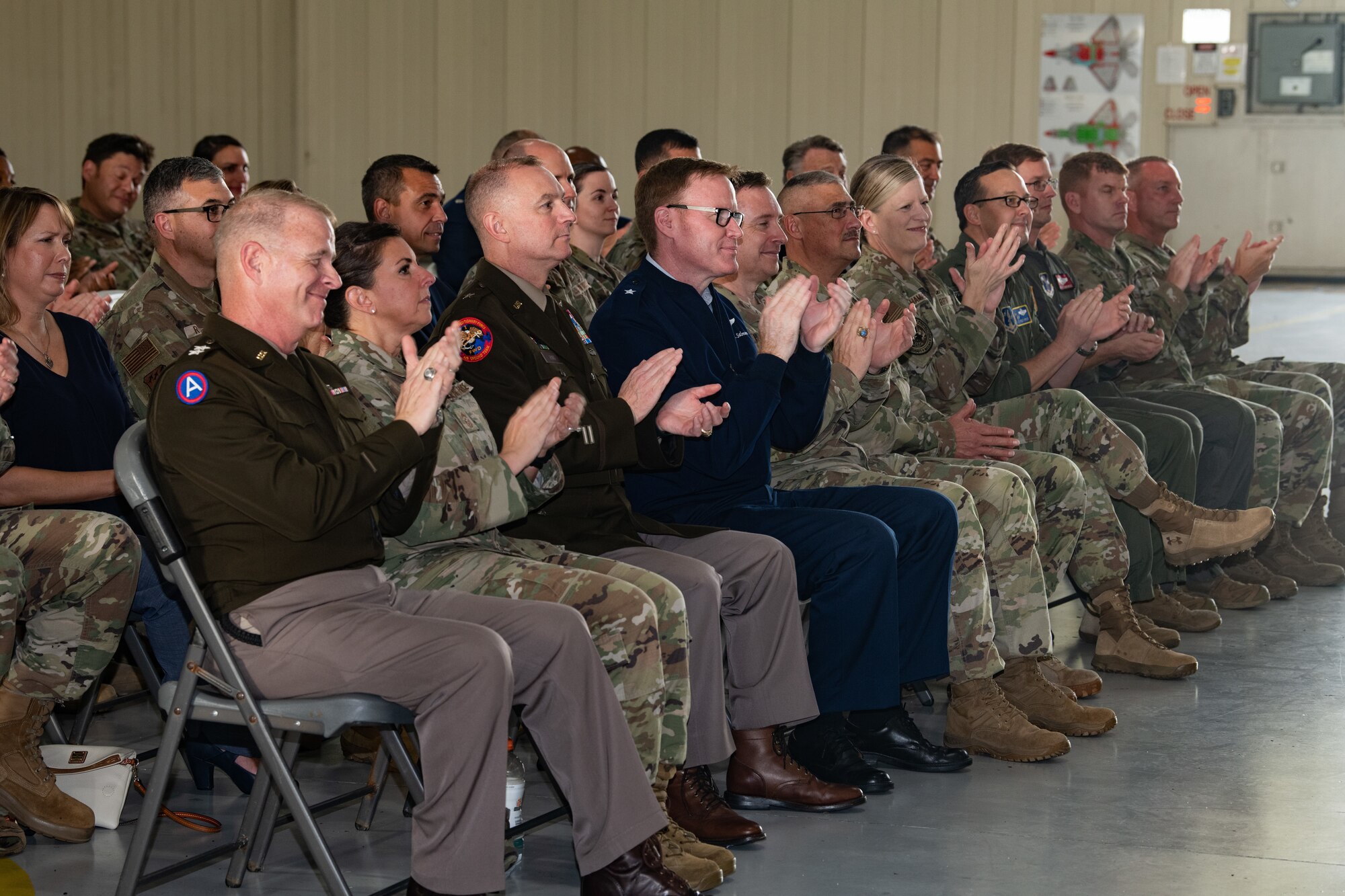 Leadership from the Virginia National Guard sit in the audience and applaud.