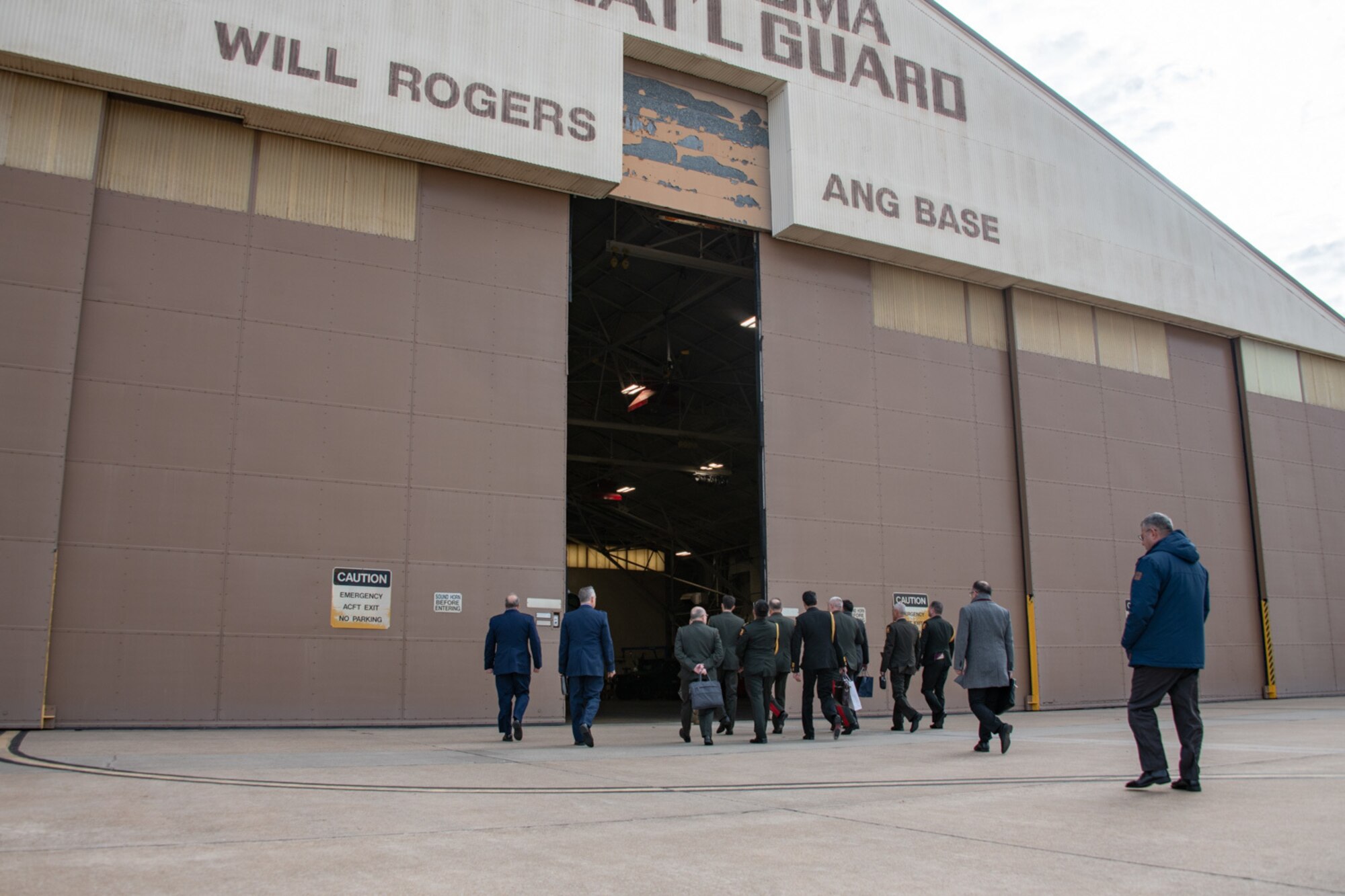 people walk into a hangar on a flightline