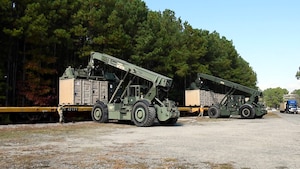 U.S. Soldiers with the 11th Transportation Battalion, 7th Transportation Brigade (Expeditionary), operate Rough Terrain Cargo Handlers to load cargo containers onto rail cars at Joint Base Langley-Eustis, Virginia, November 16, 2022. The cargo containers are filled with supplies that will support the National Science Foundation at McMurdo Station, Antarctica, which is part of Operation Deep Freeze. (U.S. Air Force photo by Abraham Essenmacher)