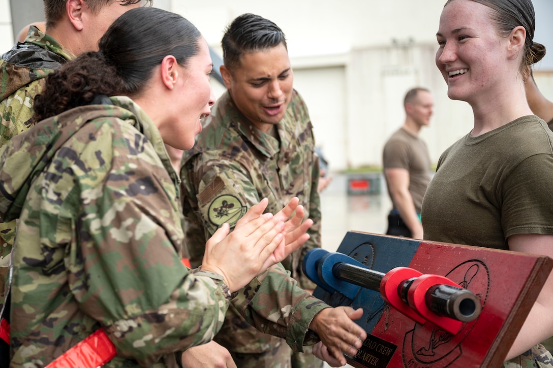 An airman smiles and holds a trophy as others admire it.