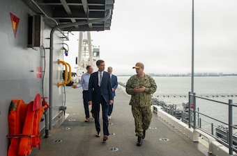 Two men walking on the ship with ocean in the background. Capt Matthew Cieslukowski in uniform on the right discussing with Revor Smith on the left.