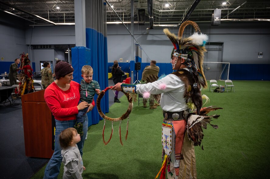 A Native American dancer at the Native American Heritage Month closing ceremony shows off his regalia to a child at Minot Air Force Base, North Dakota, Nov. 30, 2022. During the ceremony, attendees learned about Native American culture from local tribes and Native American Airmen. (U.S. Air Force photo by Airman 1st Class Alexander Nottingham)