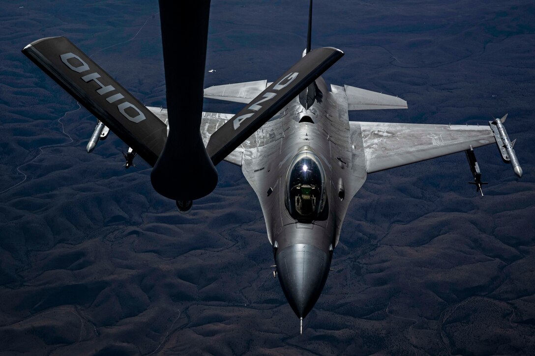 An aircraft hovers below the boom of another aircraft to receive fuel.