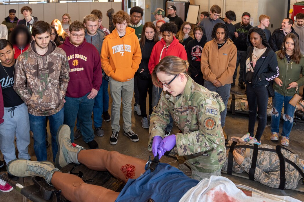 Airman applying tourniquet to dummy.