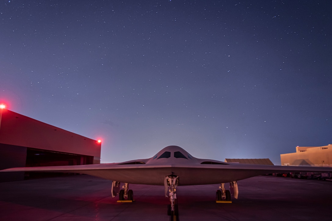 The B-21 raider aircraft sits in front of a hangar.