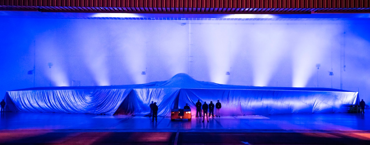 The outline of the B-21 Raider is seen through a cover before it's unveiled.