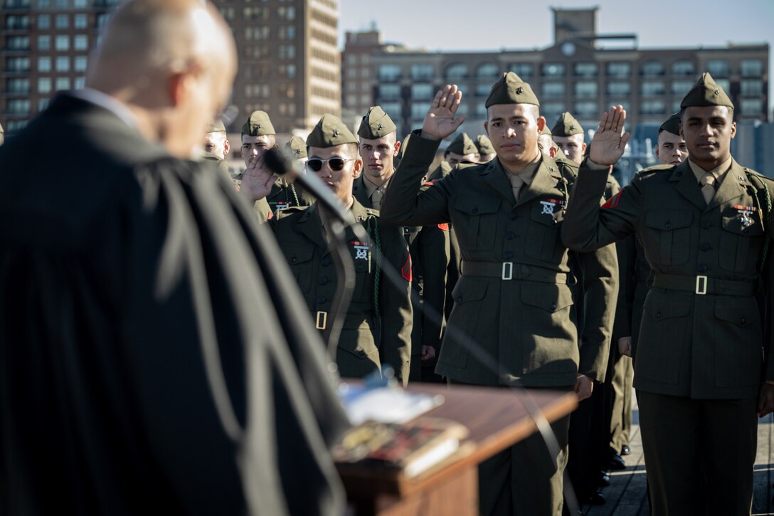 U.S. Marines from 1st Battalion, 8th Marine Regiment, raise their right hand during the Oath of Allegiance aboard the Battleship USS North Carolina, Dec. 2, 2022. 18 Marines from 15 countries and five continents swore the Oath of Allegiance and received their citizenship. Naturalization is the process by which U.S. citizenship is granted to a foreign citizen after he or she fulfills the requirements to become a citizen established by Congress in the Immigration and Nationality Act of 1965. (U.S. Marine Corps photo by Lance Cpl. Noah Seal)