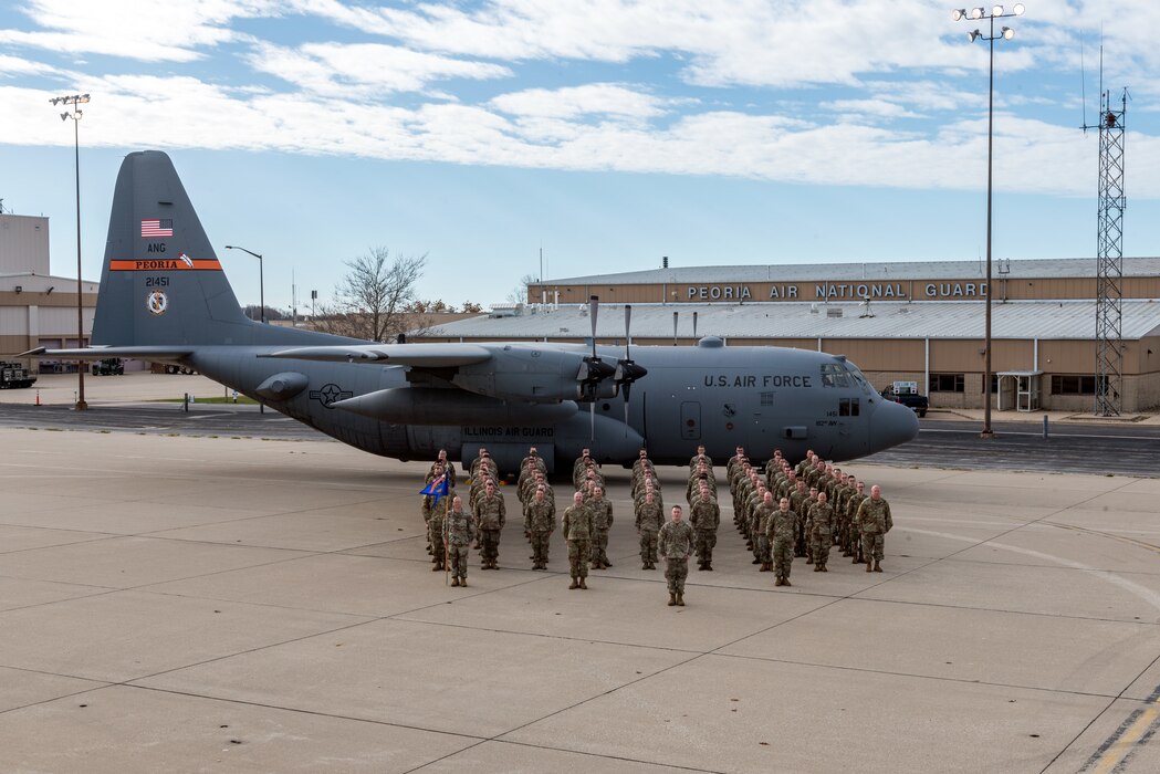 Airmen posing in front of aircraft for unit photo.