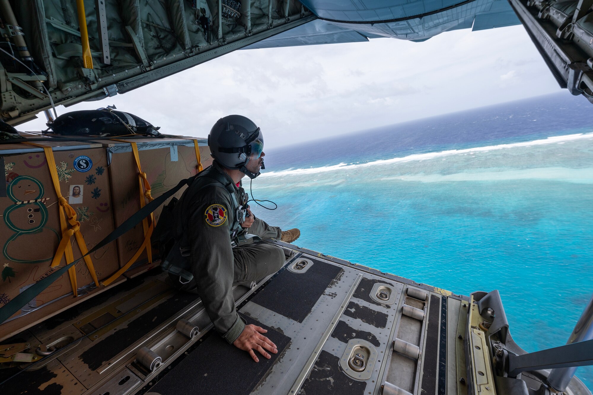 U.S. Air Force Airman 1st Class Cameron Palmer, 36th Expeditionary Airlift Squadron C-130J loadmaster, conducts a visual confirmation over Asor atoll in the Caroline Islands of the western Pacific Ocean