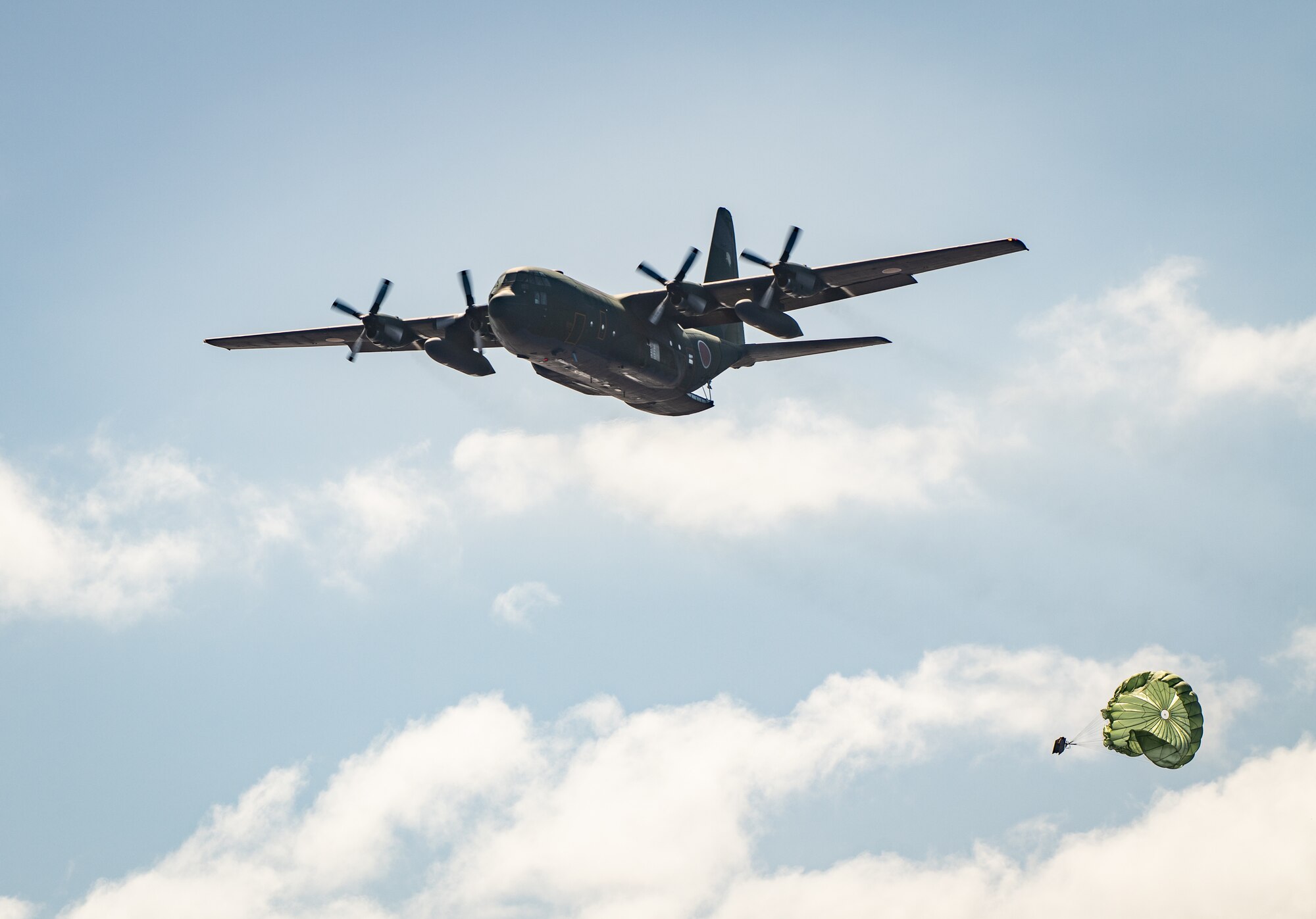 A Japan Air Self Defense Force C-130H Hercules assigned to the 401st Tactical Airlift Squadron flies over a drop zone during practice airdrop operations near Andersen Air Force Base