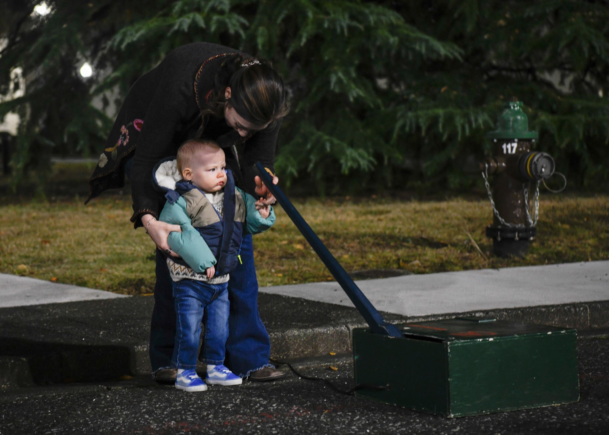 A mother and her son turn the lever to turn on the lights for the Christmas tree