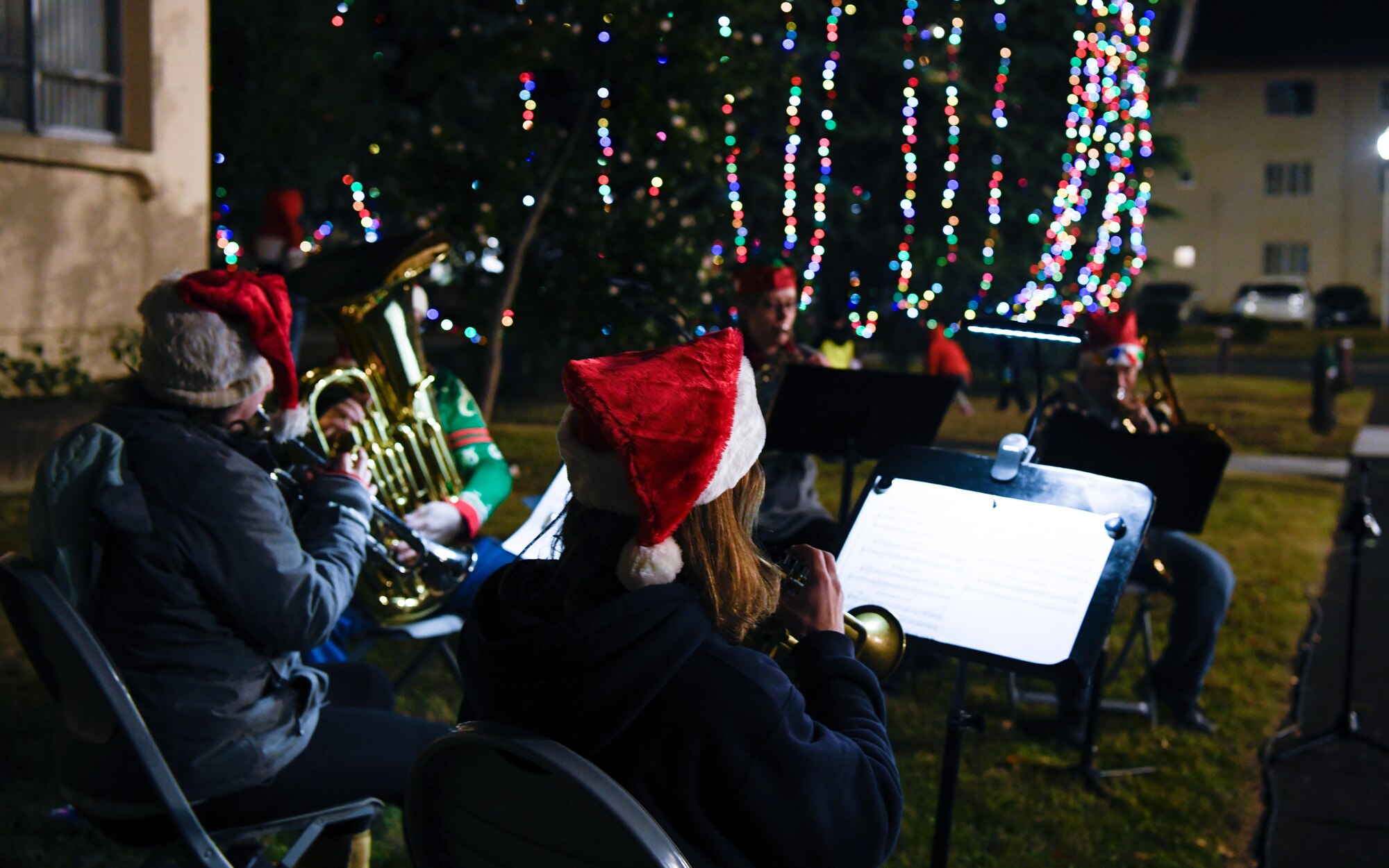 A band plays with a Christmas tree in the background.