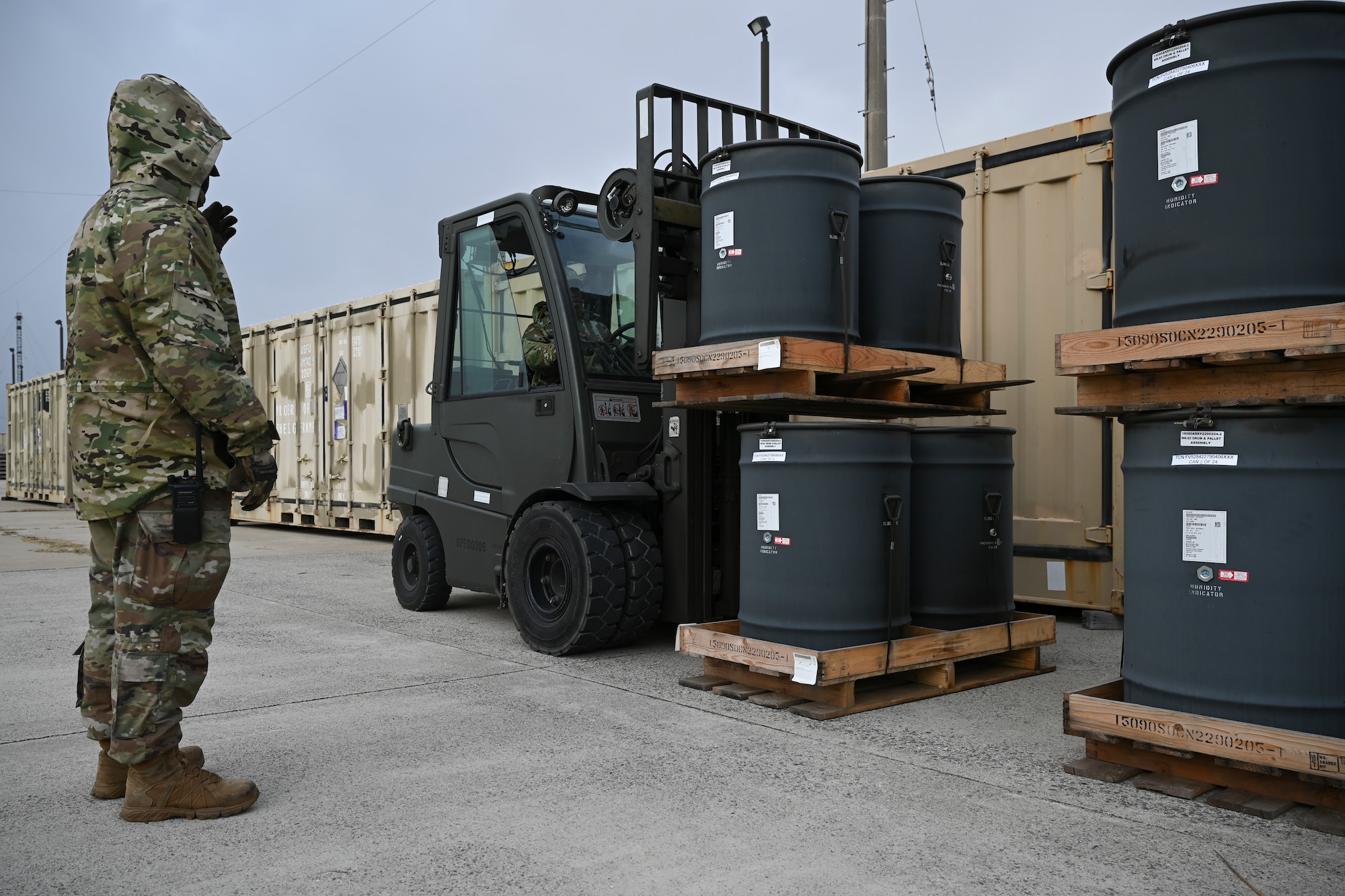An Airman directs another Airman on how to stack the munition with a warehouse forklift.