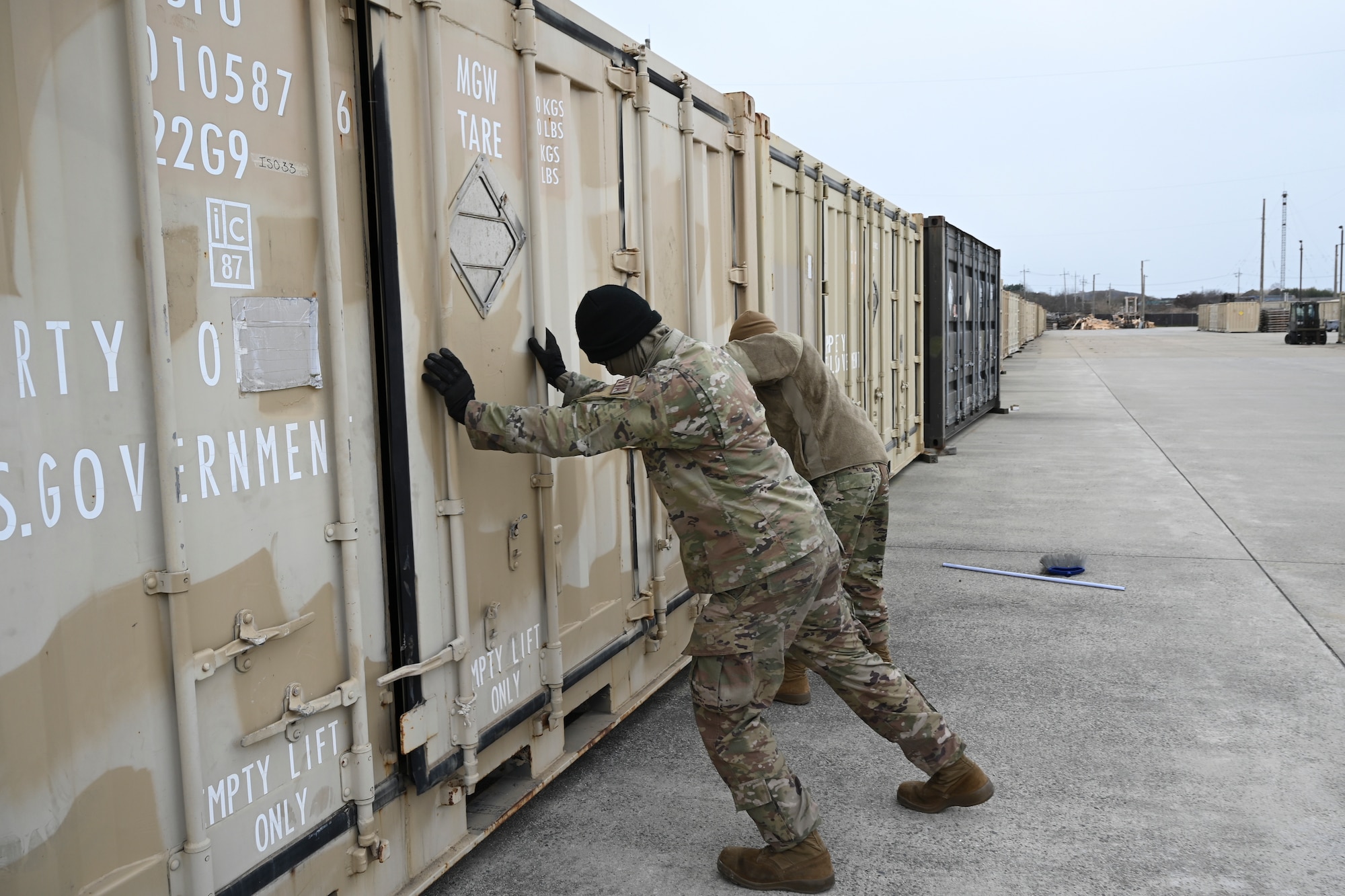 Two Airmen close the door of an intermodal shipping container.