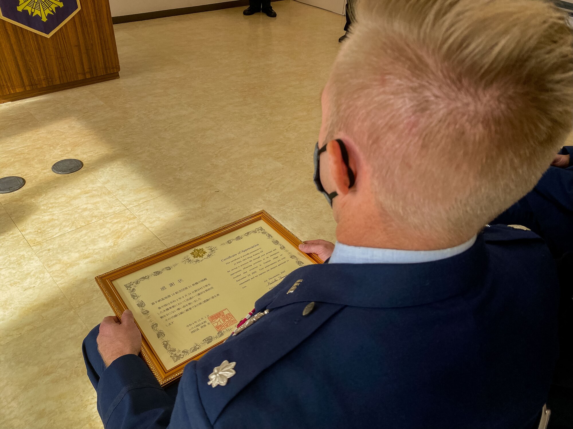 An airman sits with a certificate of appreciation