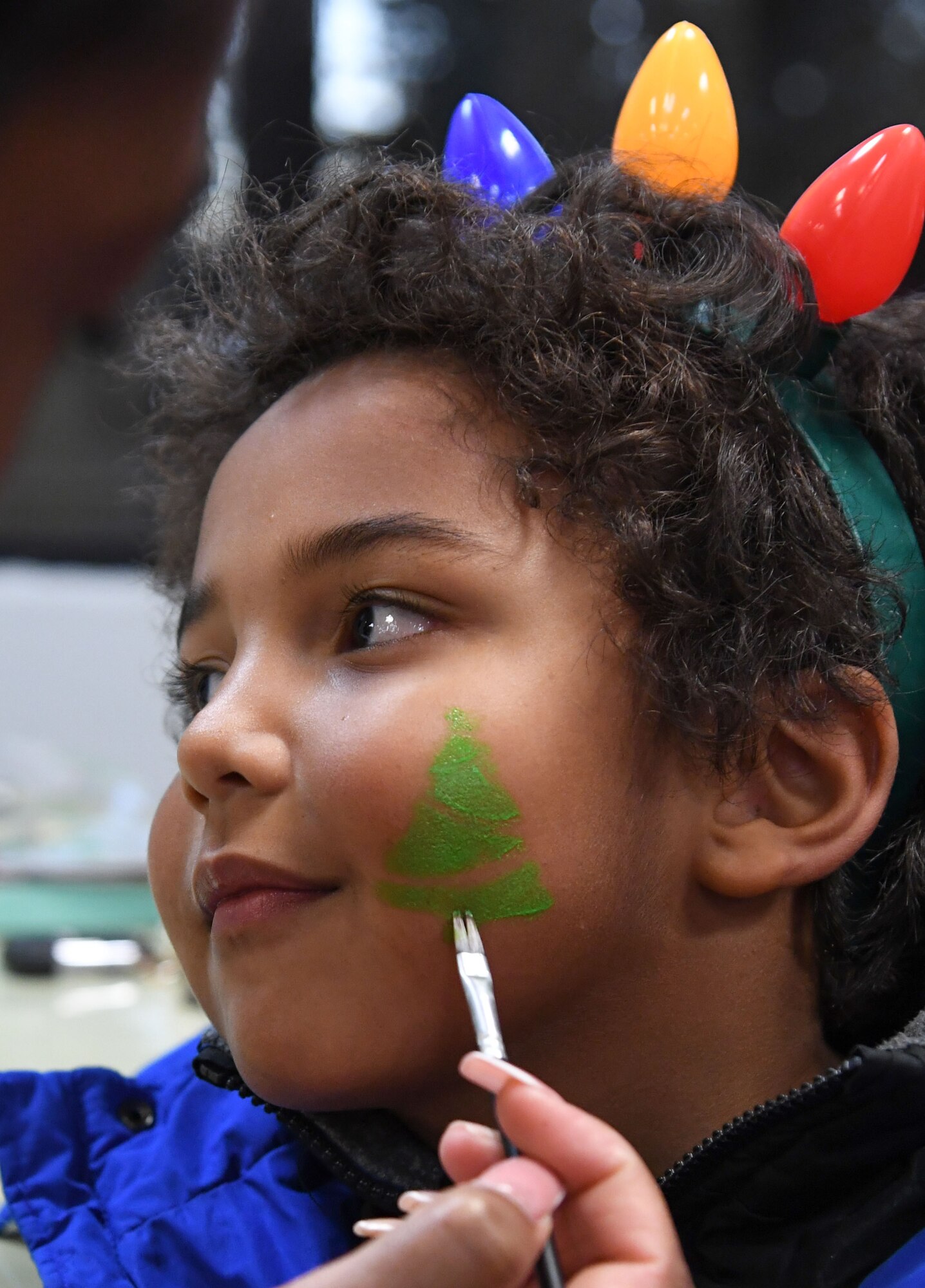 Kaiden Williams, son of U.S. Navy Equipment Operator 3rd Class Charles Mathenge, Naval Mobile Construction Battalion 11 Petty Officer 3rd Class, at the Naval Construction Battalion Center at Gulfport, Mississippi, has his face painted during Holiday in the Park at Keesler Air Force Base, Mississippi, Dec. 1, 2022.