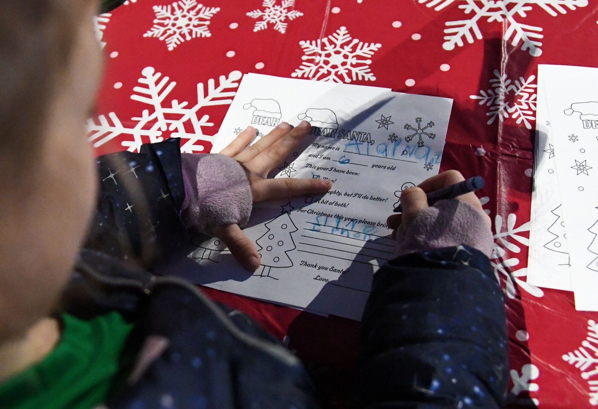 Alaina Zimmer, daughter of U.S. Navy Aviation Technician Senior Chief Robert Zimmer, Center for Naval Aviation Technical Training Unit Keesler instructor, writes a letter to Santa during Holiday in the Park at Keesler Air Force Base, Mississippi, Dec. 1, 2022.