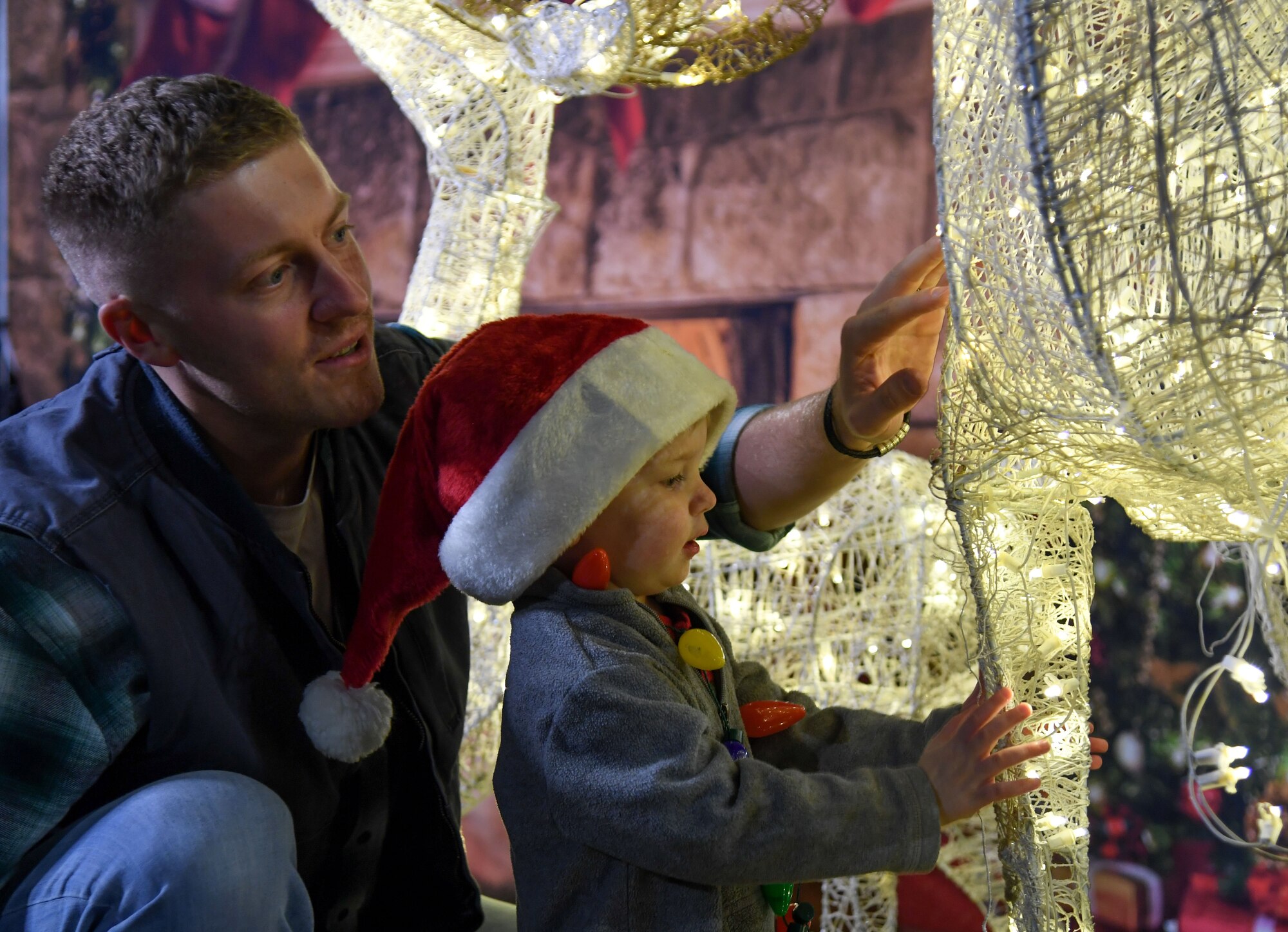 U.S. Air Force Senior Airman Shawn Jensen, 81st Diagnostic and Therapeutics Squadron radiologist technician, and his son, Aiden, inspect Christmas lights during Holiday in the Park at Keesler Air Force Base, Mississippi, Dec. 1, 2022.