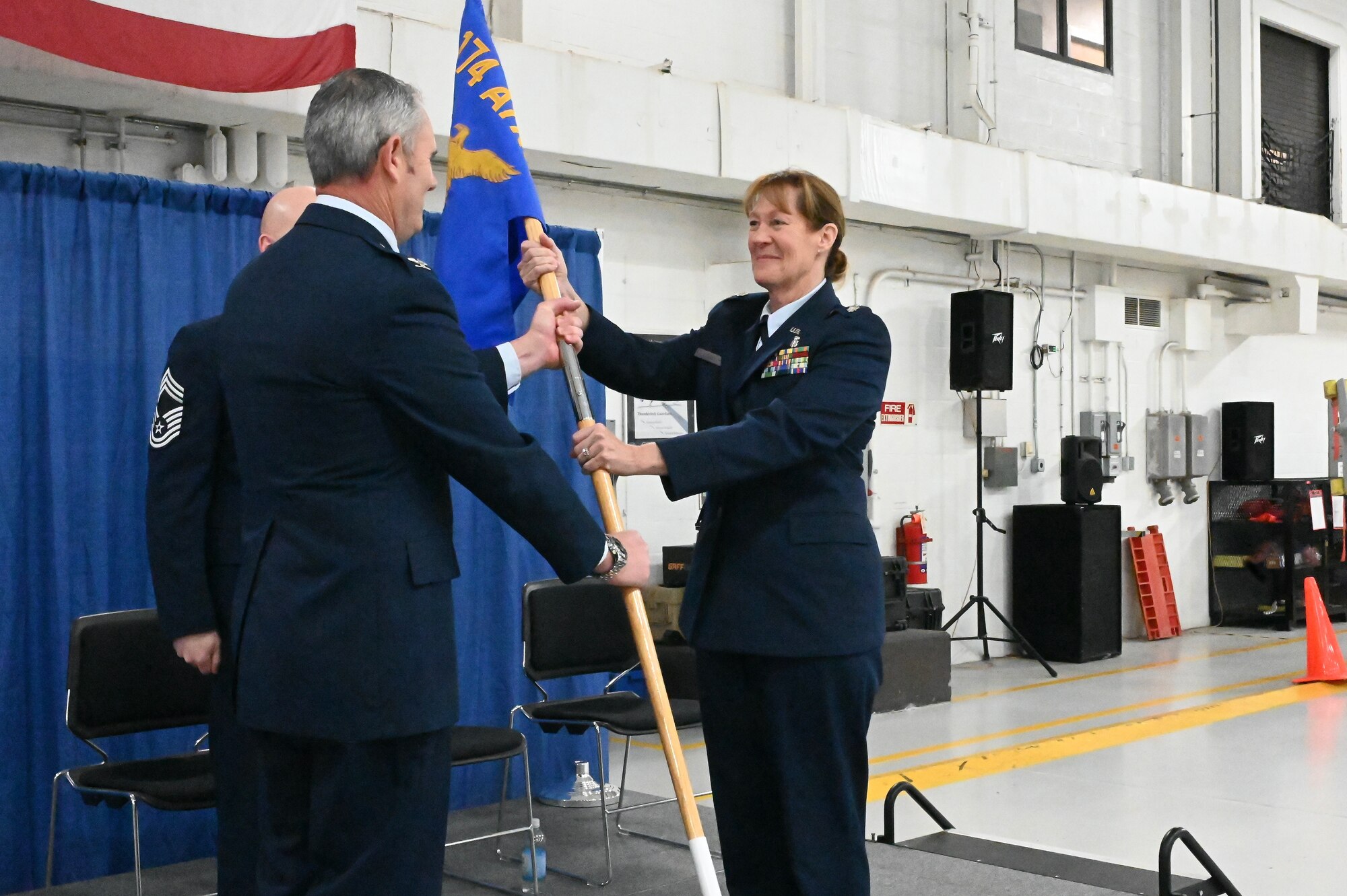 Col. William J. McCrink III (left), 174th Attack Wing commander, passes the 174th Medical Group (MDG) guidon to Lt. Col. Misty Looney during an assumption of command ceremony at Hancock Field Air National Guard Base, Dec. 3, 2022.  (U.S. Air National Guard photo by Staff Sgt. Duane Morgan)