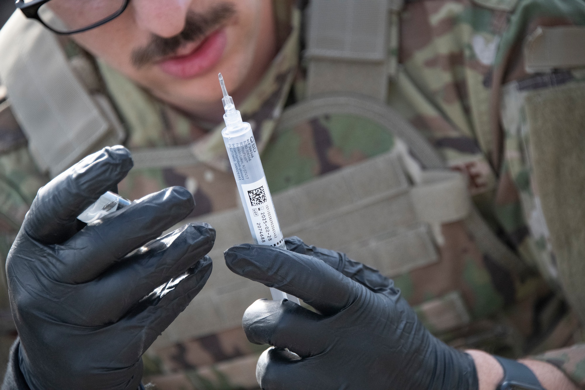 Airman looks at a syringe.