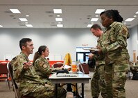 Airmen talking at a check-in desk during medical readiness event