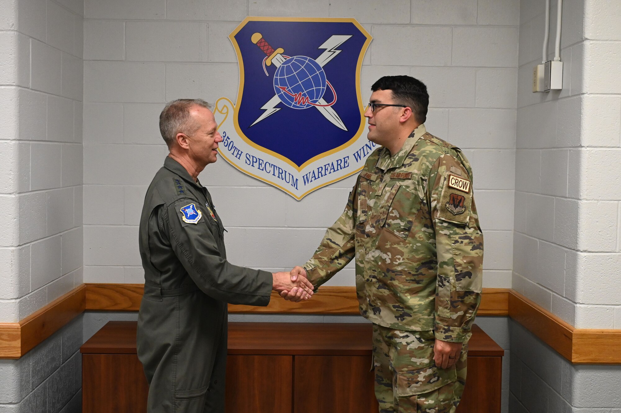 U.S. Air Force Gen. Mark Kelly, commander of Air Combat Command, coins Tech. Sgt. Brian Pagel, 87th Electronic Warfare Squadron Combat Shield avionics EW craftsman, during his visit at Eglin Air Force Base, Fla., Nov. 30, 2022. Airmen from the 350th Spectrum Warfare Wing deliver cutting-edge EW capabilities to the warfighter, while continuously improving their readiness and capabilities to compete with and deter peer competitors to win the high-end fight. (U.S. Air Force photo by 1st Lt. Benjamin Aronson)