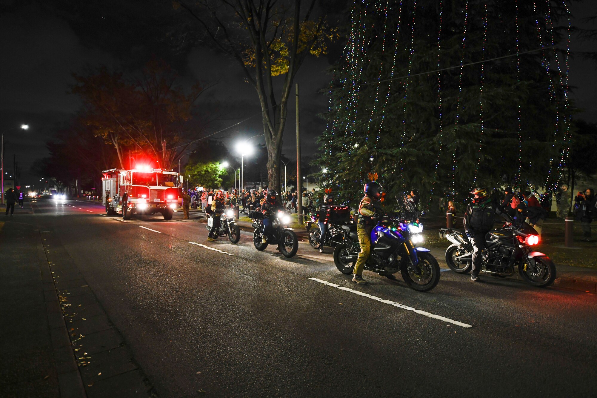Fire truck and motor cycles in front of a chapel and Christmas tree.