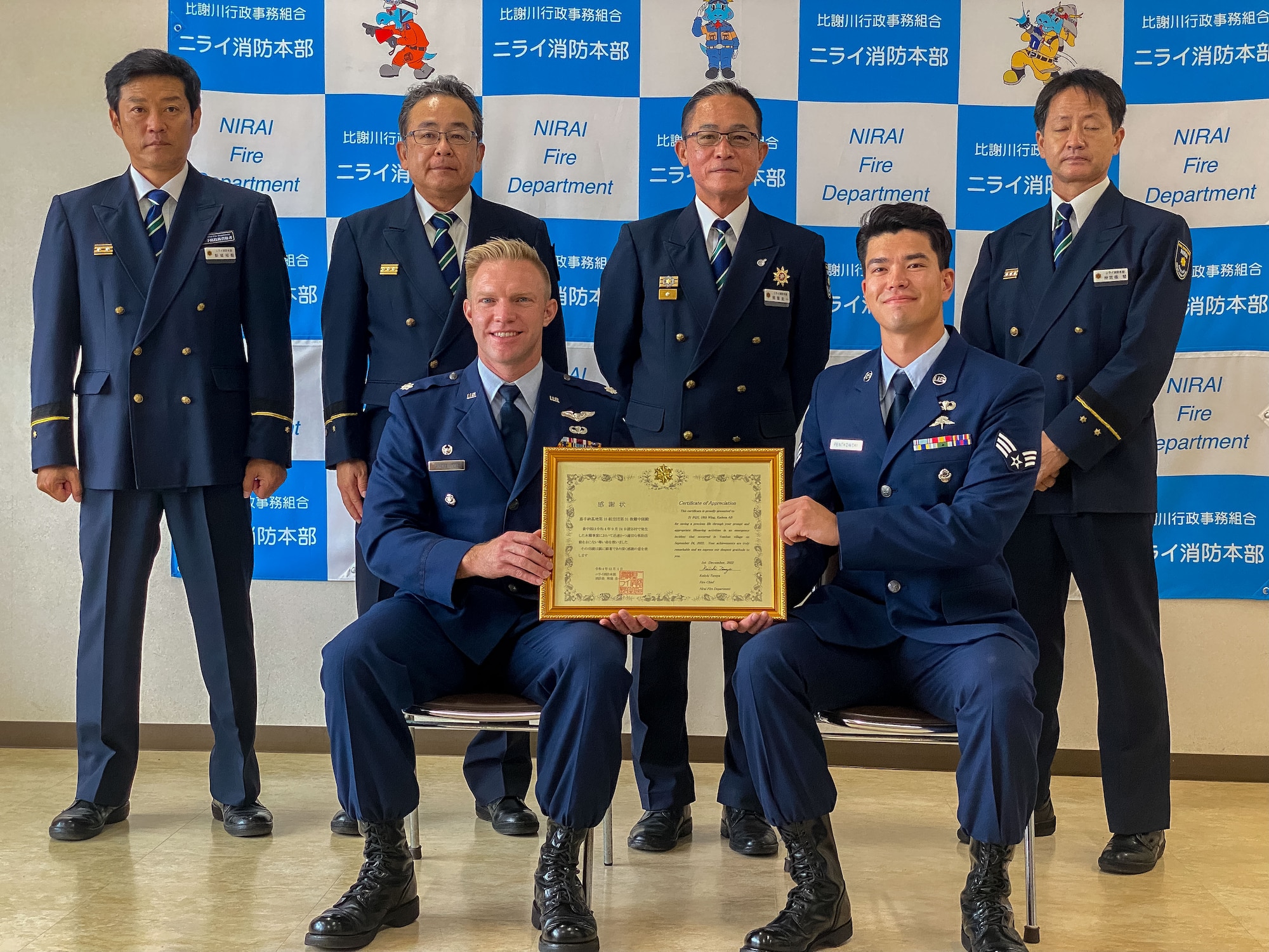 Members of a local fire department and Air Force members pose for the presentation of an award