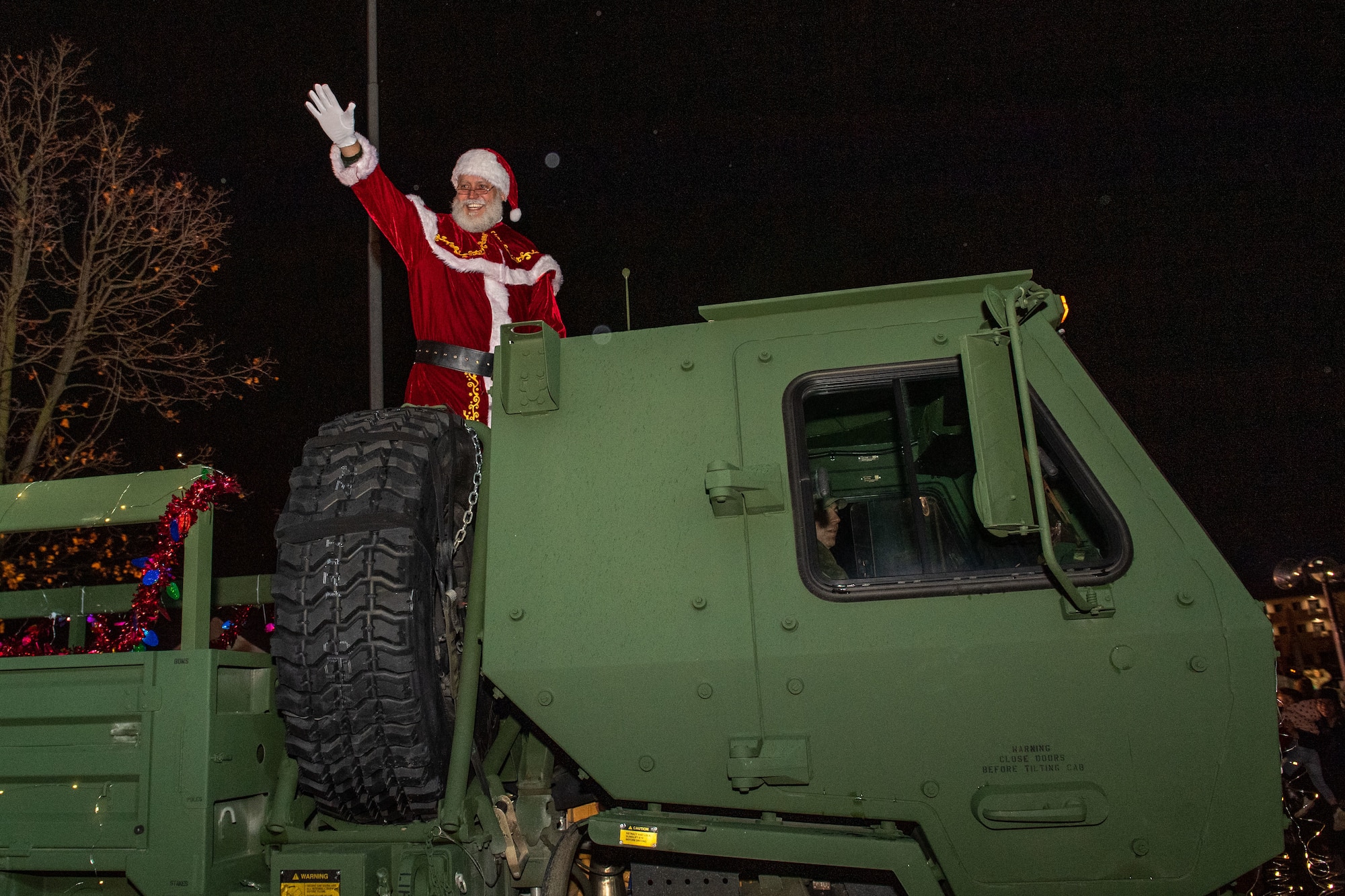 Santa Claus, North Pole gift-giver, waves to the crowd as he is escorted onto base during the Wyvern Wonderland holiday event at Aviano Air Base