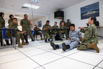 Hospital Corpsman 1st Class Tiny Rose Medallo, far right, with Commander, U.S. 7th Fleet, demonstrates the appliance of a tourniquet on a Royal Malaysian Navy sailor for a Combat Life Saving class during Cooperation Afloat Readiness and Training (CARAT) Malaysia 2022 on the Joint Forces Headquarters Base, Pahang, Malaysia, Nov. 23, 2022.