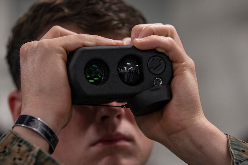 Close up of a Marine looking through a laser range finder.