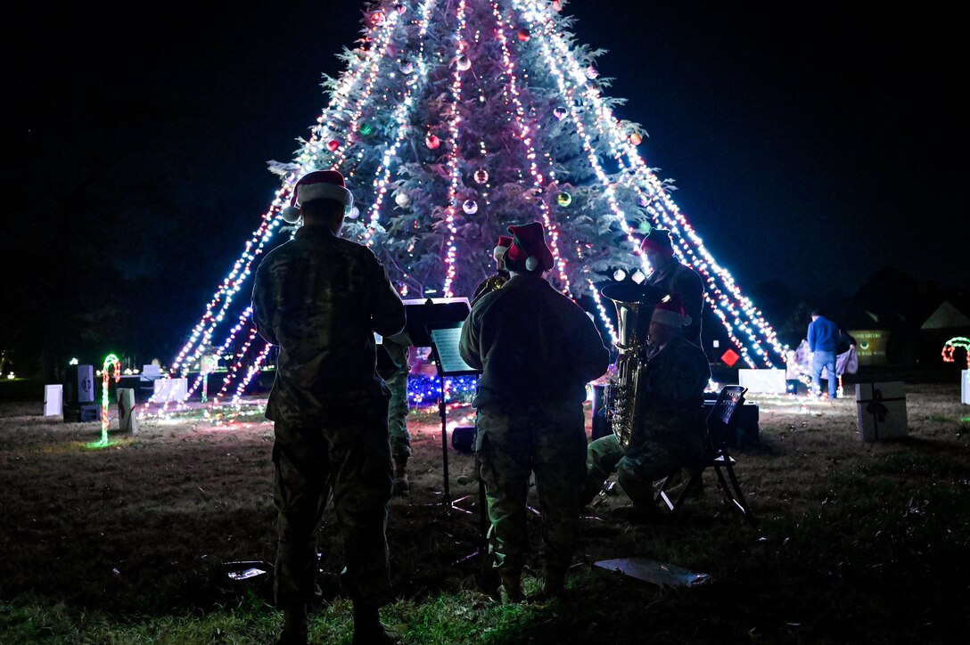 Band playing music in front of holiday tree.